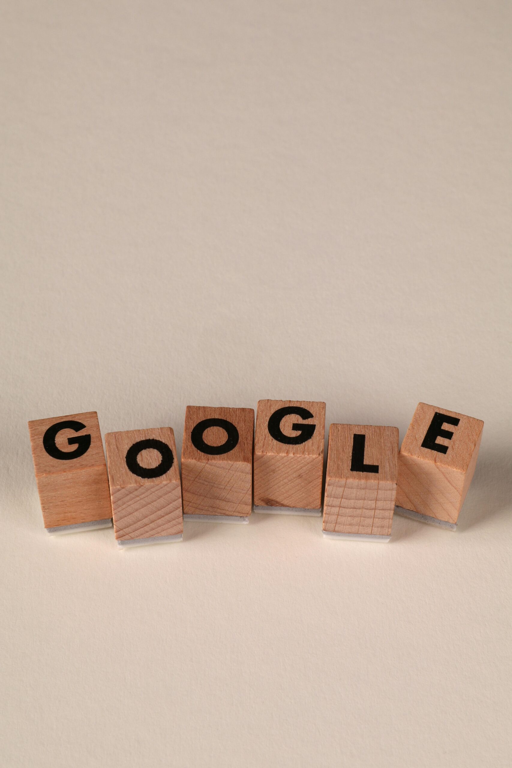 Wooden alphabet blocks forming the word 'Google' on a plain background, arranged playfully.